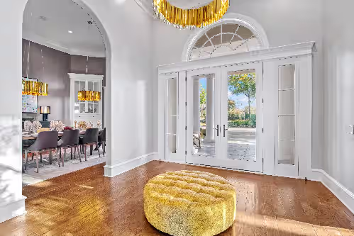 Step into luxury—this stunning foyer greets you with soaring ceilings, rich textures, and a sculptural gold circular seat
